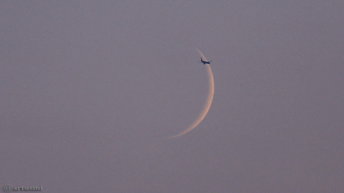 Flugzeug passiert schmale Mondsichel