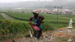 terroir f Sommerhausen - Skulptur "zum Wohl" von Melina Hillion und Peter Brander - rechts davon die Figur "Bachus 2014" von Bernhard Schwanitz