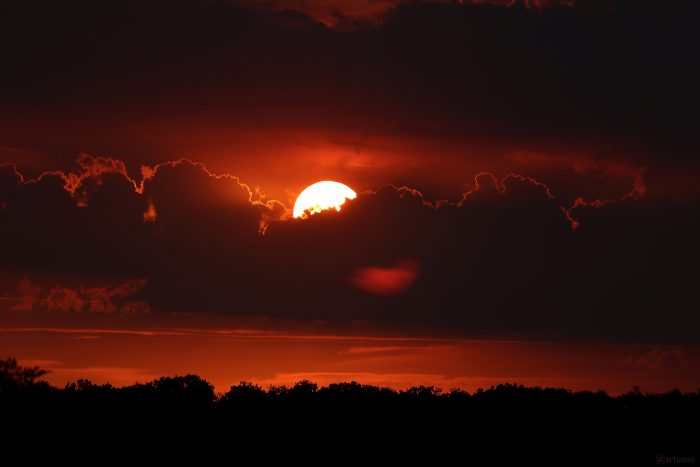 Untergehende Sonne hinter Wolken am 19. August 2022