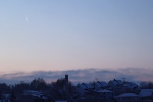Abnehmender Mond am Morgen des 19. Januar 2023 über der Philippuskirche in Eisingen.