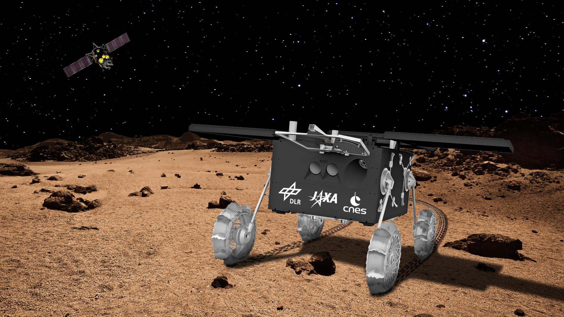 Künstlerische Darstellung des MMX-Rovers: Am Ziel angekommen: Nach dem Ausklinken durch das Mutterschiff (im Hintergrund) und dem Fall zur Phobos-Oberfläche hat sich der MMX-Rover selbstständig aufgerichtet und mit Energie versorgt. Nun ist er bereit für die Erkundung des Marsmondes.