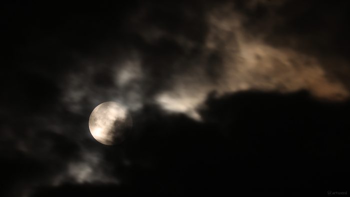 Vollmond am 18. September 2024 zu Beginn der partiellen Phase hinter Wolken