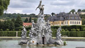Musenberg Parnass mit dem Gott Apollon, den Musen und dem geflügelten Pferd Pegasus. Im Hintergrund ist das Schloss Veitshöchheim zu sehen.