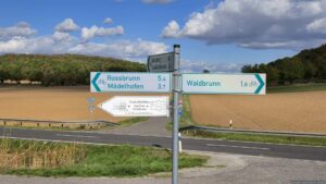 Hier überqueren wir die Kreisstraße WÜ 12, die links zur Einmündung in die Staatsstraße 2312 und rechts nach Waldbrunn führt.
